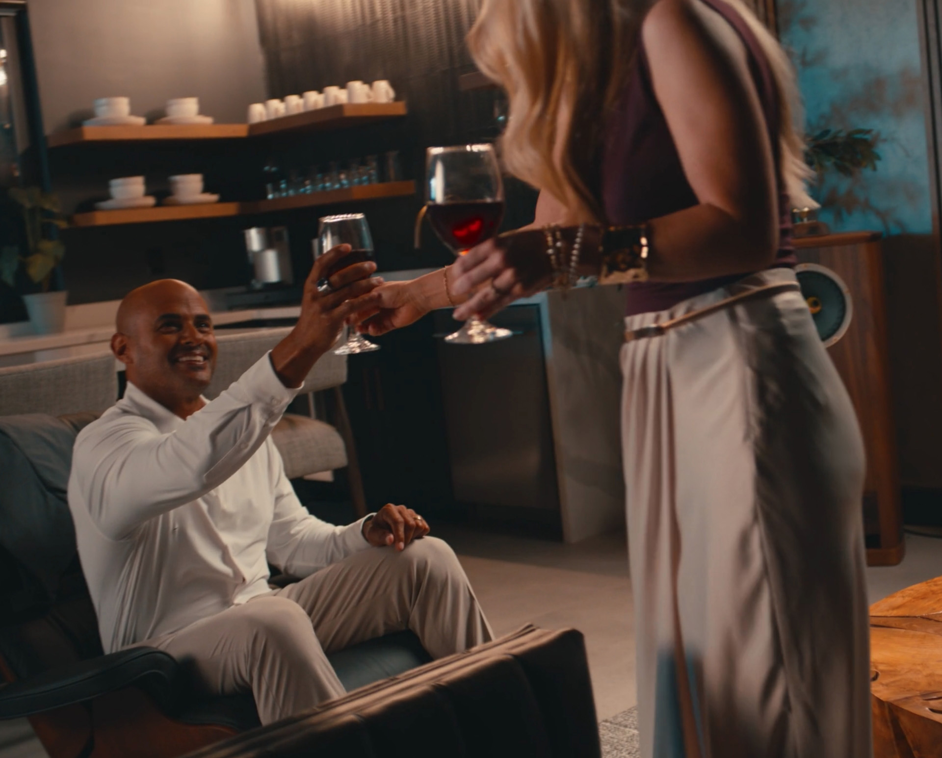 Woman handing wine glass to man on the couch